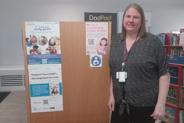 Image depicts a librarian next to the breastfeeding friendly poster.