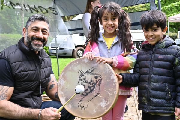 An adult holding a drum with two children