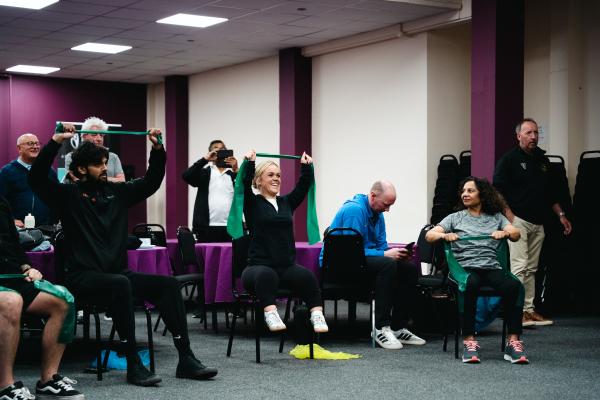 Image depicts a group of people taking part in a group exercise.