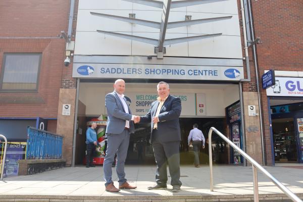 cllr adrian andrew with Kier representative stand shaking hands in front of the saddlers shopping centre