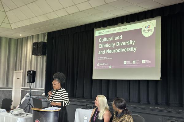 Image depicts Dr Venessa Swaby giving a PowerPoint presentation at the Neurodiversity conference.