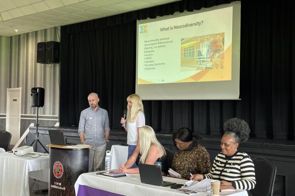 Image depicts Tom and Tracy from 3SC giving a PowerPoint presentation at the Neurodiversity Conference.