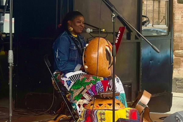 Millicent Chapanda winking at the camera, playing a mbira