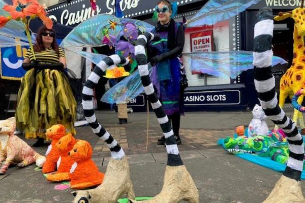 A group of people dressed in bright festival clothes and masks with papier mache animals