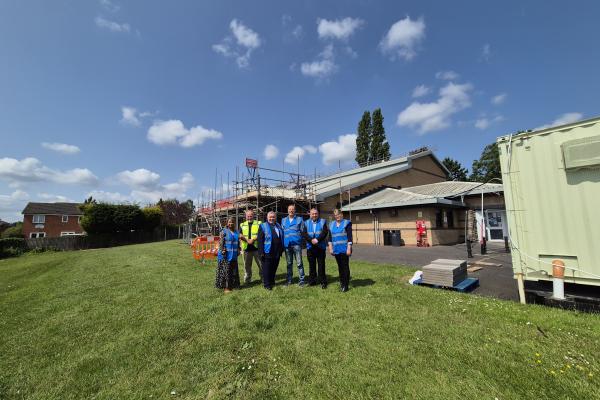 A group in high vis jackets stand in front of a building with scaffolding